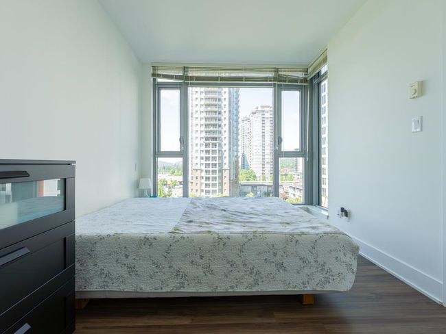 Bedroom with multiple windows, dark wood finished floors, and a view of city | Image 12