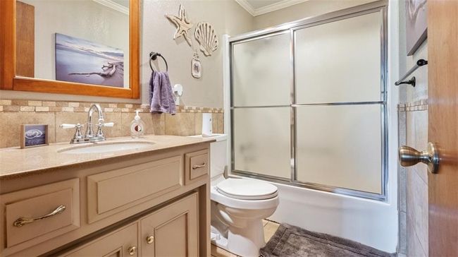 Bathroom with crown molding, vanity, combined bath / shower with glass door, and backsplash | Image 18