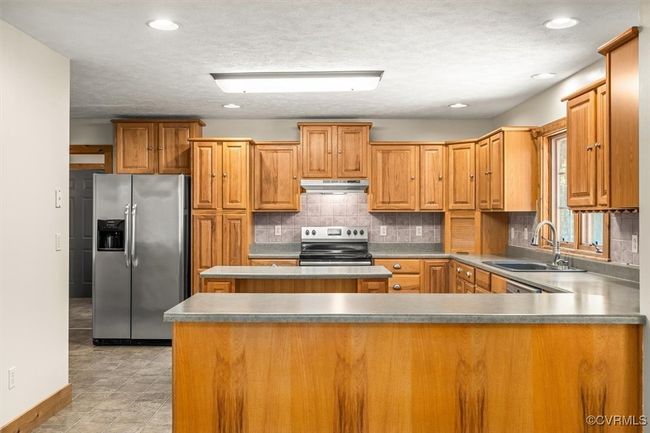 Kitchen with a textured ceiling, stainless steel appliances, sink, and decorative backsplash | Image 33