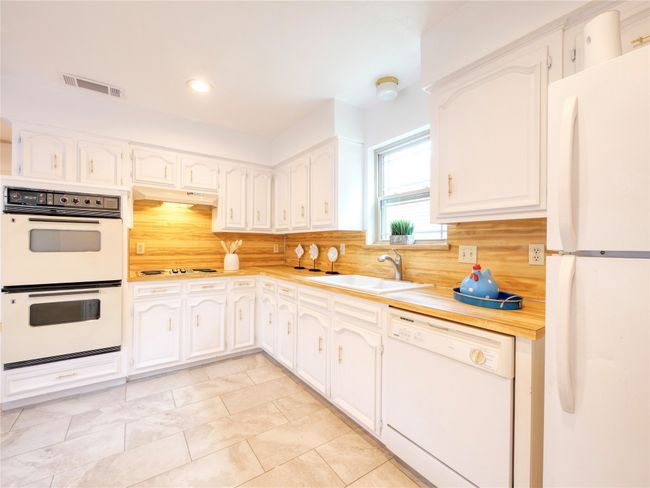 Kitchen featuring white appliances, decorative backsplash, light countertops, white cabinetry, and recessed lighting | Image 14