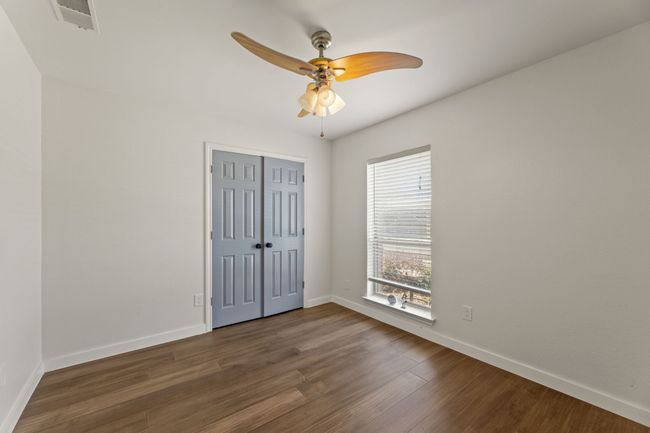 Unfurnished bedroom with a closet, a ceiling fan, baseboards, visible vents, and dark wood-style flooring | Image 19