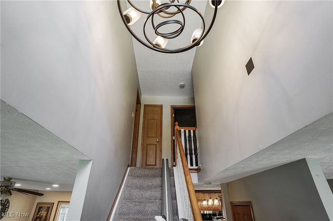 Stairs featuring a textured ceiling and ceiling fan with notable chandelier | Image 26