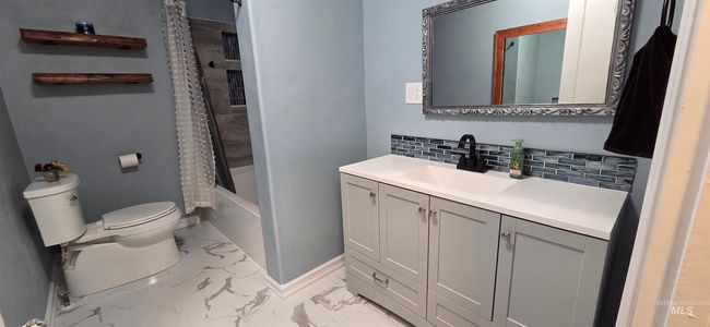 Full bath featuring marble finish floors, vanity, backsplash, and shower / tub combo with curtain | Image 11