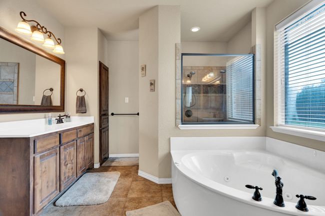 Bathroom featuring a jetted tub, vanity, plenty of natural light, and baseboards | Image 12