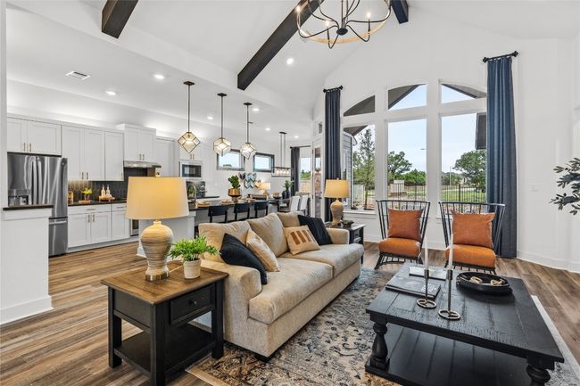 Living area with beam ceiling, wood finished floors, recessed lighting, a chandelier, and high vaulted ceiling | Image 9