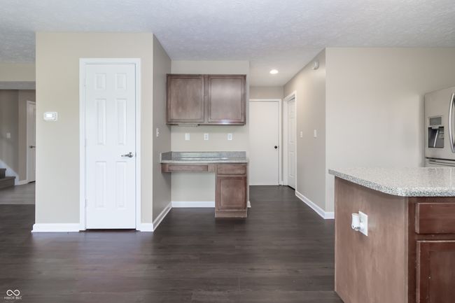 kitchen with fridge with ice dispenser, dark wood-style floors, a textured ceiling, built in study area, and recessed lighting | Image 11