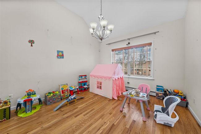 Rec room with a chandelier, baseboard heating, wood finished floors, lofted ceiling, and baseboards | Image 14
