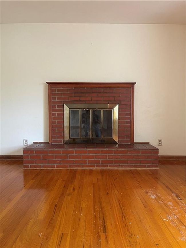 Room details featuring a brick fireplace, wood finished floors, and baseboards | Image 9
