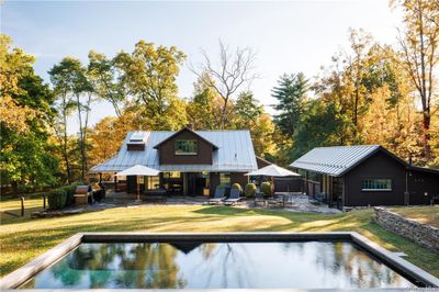 Rear view of house with a pool, patio, and a lawn | Image 1