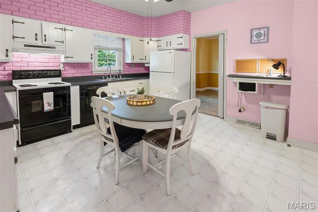 Kitchen with electric range oven, black dishwasher, freestanding refrigerator, under cabinet range hood, and dark countertops | Image 18