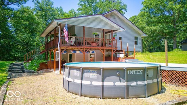 rear view of house featuring stairs, a deck, and an outdoor pool | Image 9