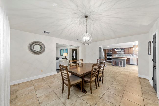 Dining room featuring light tile patterned floors, visible vents, a notable chandelier, and baseboards | Image 25