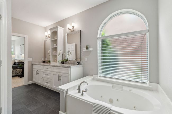 Bathroom with ensuite bathroom, double vanity, a jetted tub, and tile patterned floors | Image 19