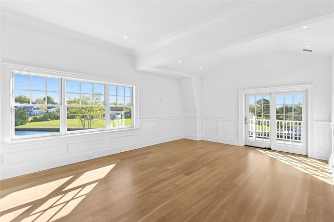 Primary bedroom with a decorative wall, healthy amount of natural light, vaulted ceiling, a fireplace with flush hearth, and ornamental molding | Image 21