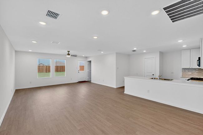 Unfurnished living room featuring recessed lighting, baseboards, wood finished floors, a sink, and ceiling fan | Image 4