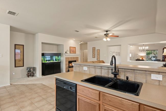 Spacious kitchen features tiled backsplash, abundant cabinet storage, laminate counters, black appliances, and a central island with butcher block top! | Image 18