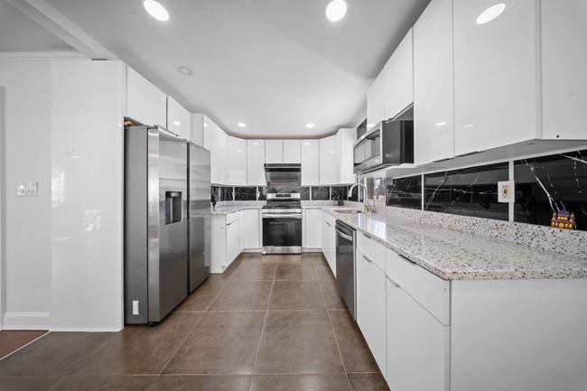 Kitchen featuring backsplash, recessed lighting, appliances with stainless steel finishes, white cabinets, and modern cabinets | Image 5