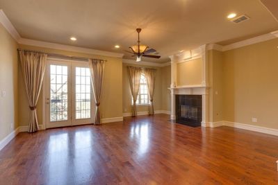 Unfurnished living room featuring ornamental molding, a tile fireplace, ceiling fan, french doors, and hardwood / wood-style flooring | Image 3