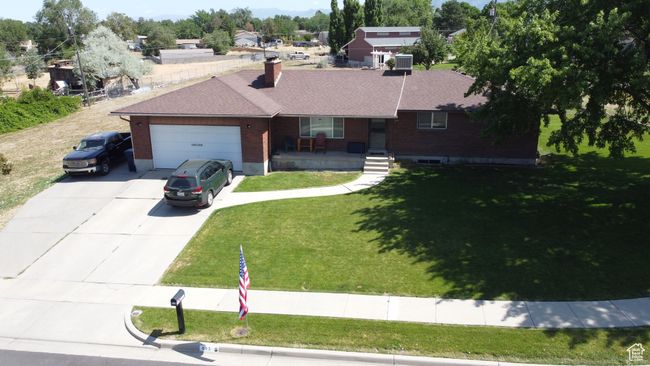 Ranch-style home with covered porch, concrete driveway, a garage, brick siding, and a chimney | Image 9