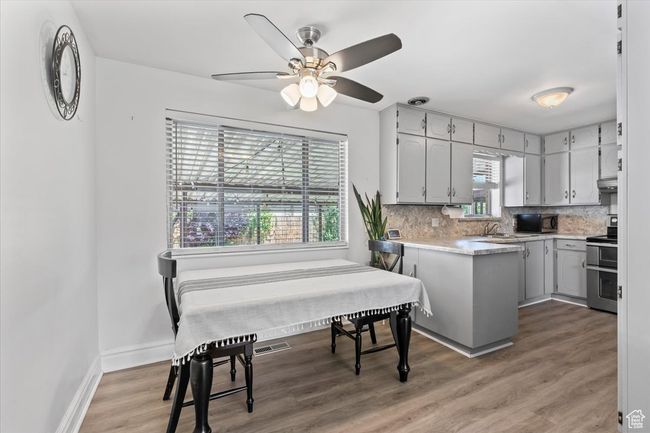 Kitchen featuring stainless steel range with electric stovetop, black microwave, backsplash, light countertops, and a ceiling fan | Image 8