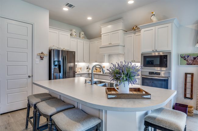 Kitchen with stainless steel appliances, white cabinetry, tasteful backsplash, light countertops, and light wood-style floors | Image 11
