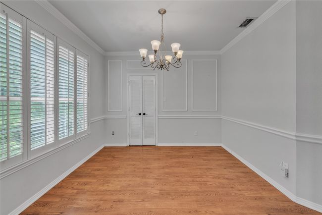 Unfurnished dining area featuring plenty of natural light, a chandelier, light wood finished floors, and crown molding | Image 8