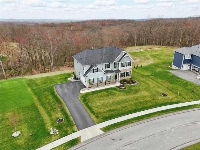 Aerial view of a beautifully maintained two-story home set on a spacious lot with expansive green lawn and private wooded backdrop. Located on a quiet cul-de-sac, this property offers scenic views, a paved driveway, and excellent curb appeal. | Image 4