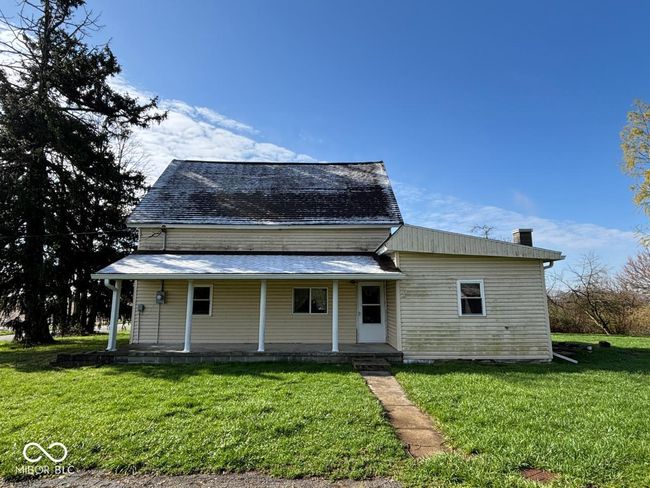 view of front facade featuring a front lawn, covered porch, and a chimney | Image 17