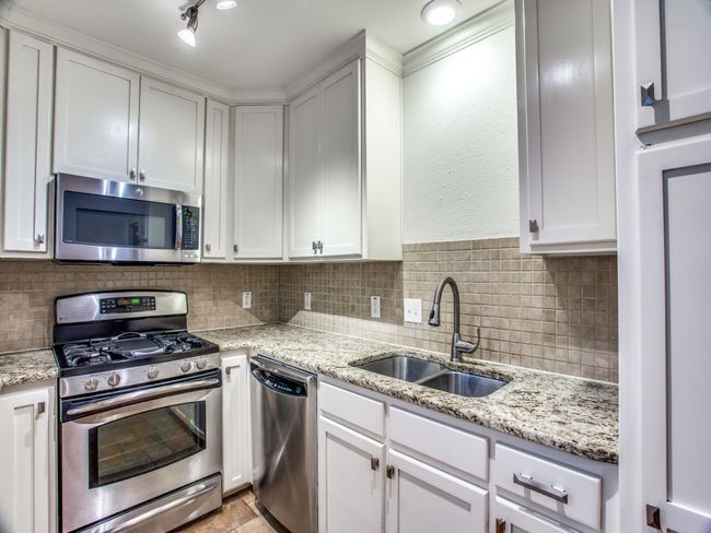 Kitchen with a sink, backsplash, appliances with stainless steel finishes, and white cabinetry | Image 11