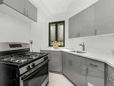 Kitchen with light stone countertops, gray cabinetry, sink, and stainless steel gas stove | Image 3