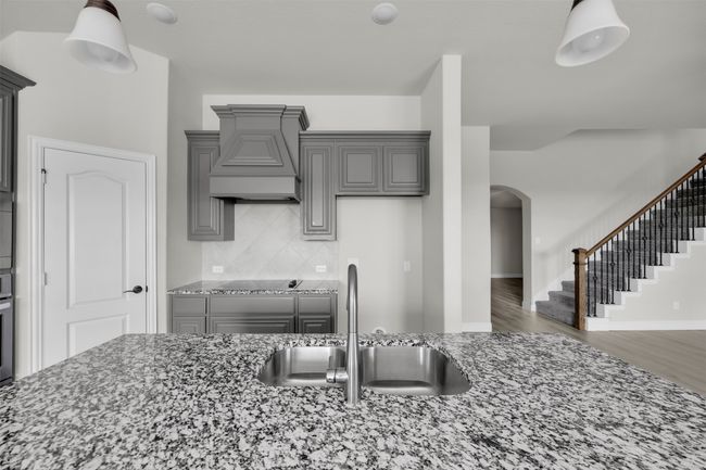 Kitchen featuring gray cabinetry, custom exhaust hood, sink, wood-style floors, and light stone countertops | Image 18