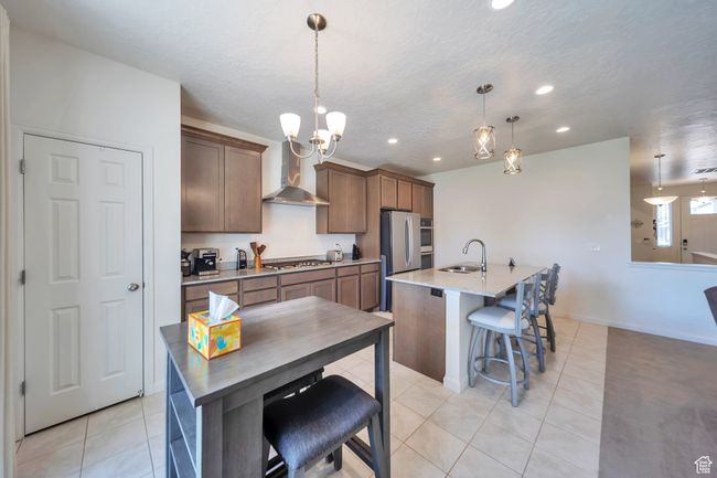 Kitchen with stainless steel appliances, a sink, recessed lighting, wall chimney range hood, and light tile patterned floors | Image 5