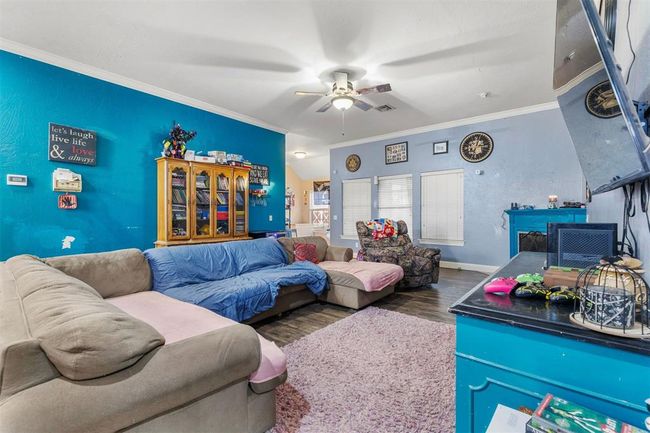 Living room featuring dark wood-type flooring, ceiling fan, and ornamental molding | Image 4