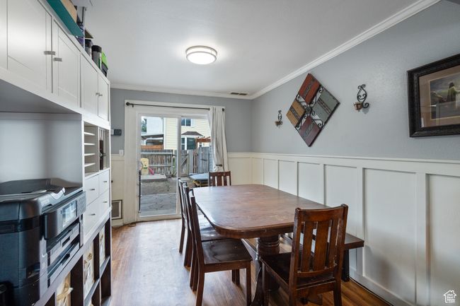 Dining area with crown molding, light wood-type flooring, wainscoting, and a decorative wall | Image 9