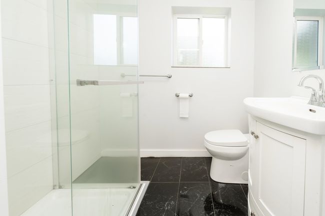Bathroom featuring baseboards, a shower stall, vanity, toilet, and marble look tile flooring | Image 22