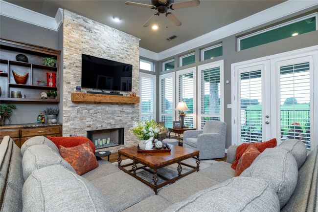 Living area with beautiful stone fireplace, custom cabinetry and ornamental molding | Image 15