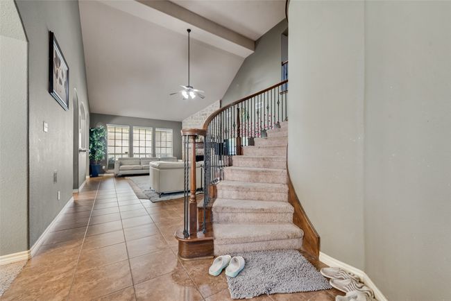 Staircase with ceiling fan, tile patterned floors, beam ceiling, and high vaulted ceiling | Image 6
