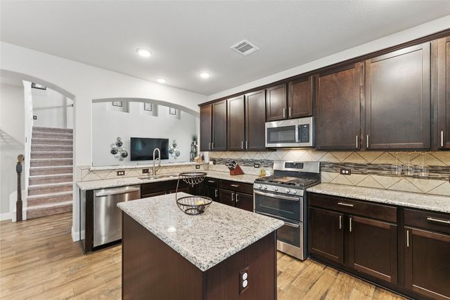 Kitchen with stainless steel appliances, tasteful backsplash, dark brown cabinetry, and visible vents | Image 13