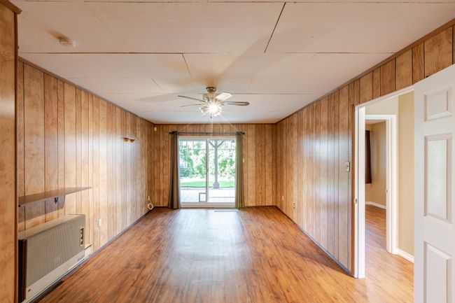 Recreation room with light wood-type flooring, radiator, wood walls, and ceiling fan | Image 29