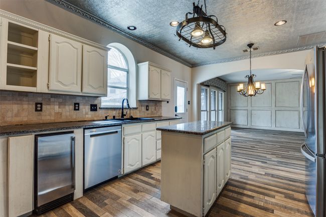 Kitchen featuring backsplash, a kitchen island, ornamental molding, appliances with stainless steel finishes, and a sink | Image 15