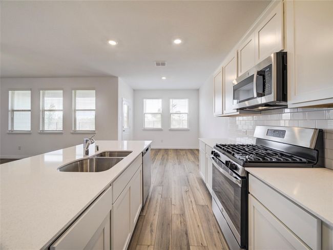 Kitchen featuring stainless steel appliances, a sink, light wood-style floors, light countertops, and recessed lighting | Image 6