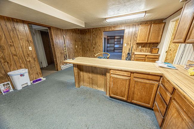 Kitchen featuring light carpet, wooden walls, and a textured ceiling | Image 44