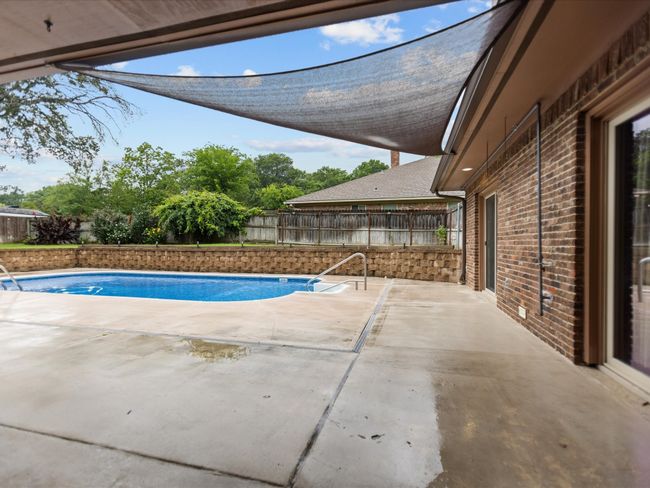 View of swimming pool featuring a fenced backyard and a patio area | Image 10