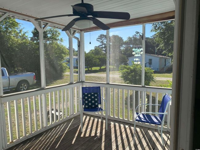Unfurnished sunroom featuring a ceiling fan and view of scattered trees | Image 15