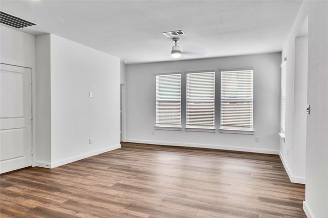 Empty room with ceiling fan, wood finished floors, visible vents, and baseboards | Image 4