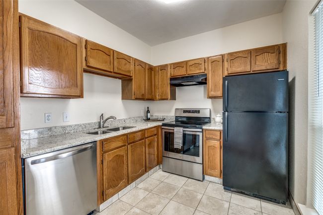 Kitchen with a sink, stainless steel appliances, under cabinet range hood, and brown cabinets | Image 9