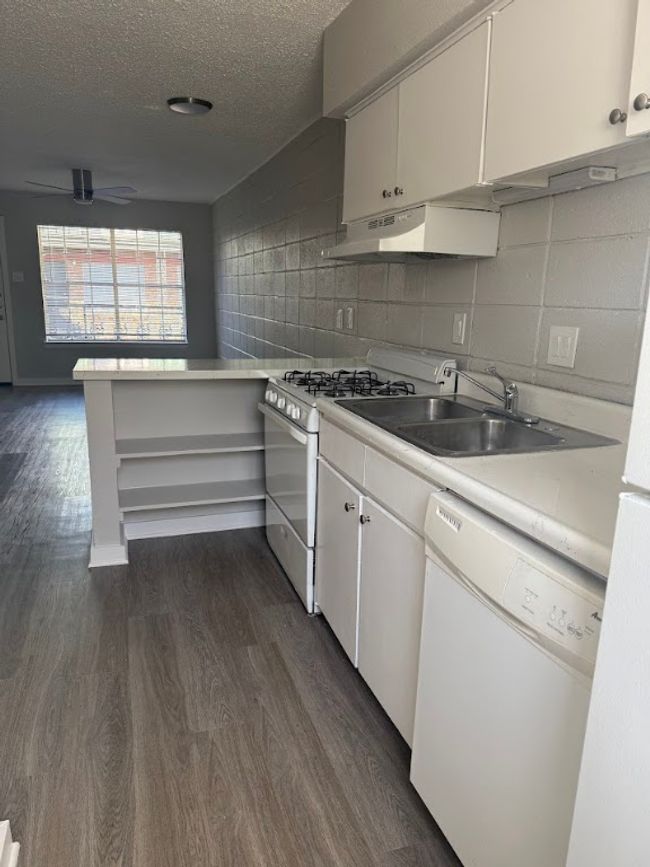 Kitchen featuring white appliances, dark wood-style floors, light countertops, white cabinetry, and a sink | Image 9