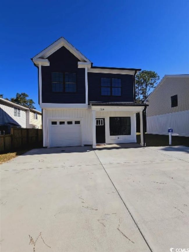 View of front of property with board and batten siding, concrete driveway, fence, and an attached garage | Image 20
