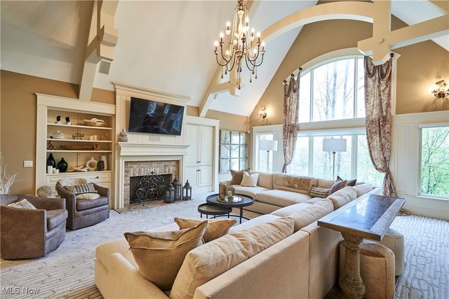 Great room with a chandelier, high vaulted ceiling, arched beams, and a brick faced fireplace with built ins | Image 4