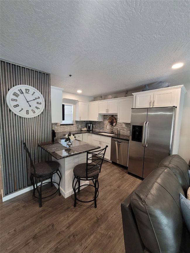 Kitchen featuring white cabinets, dark hardwood / wood-style flooring, stainless steel appliances, sink, and kitchen peninsula | Image 7